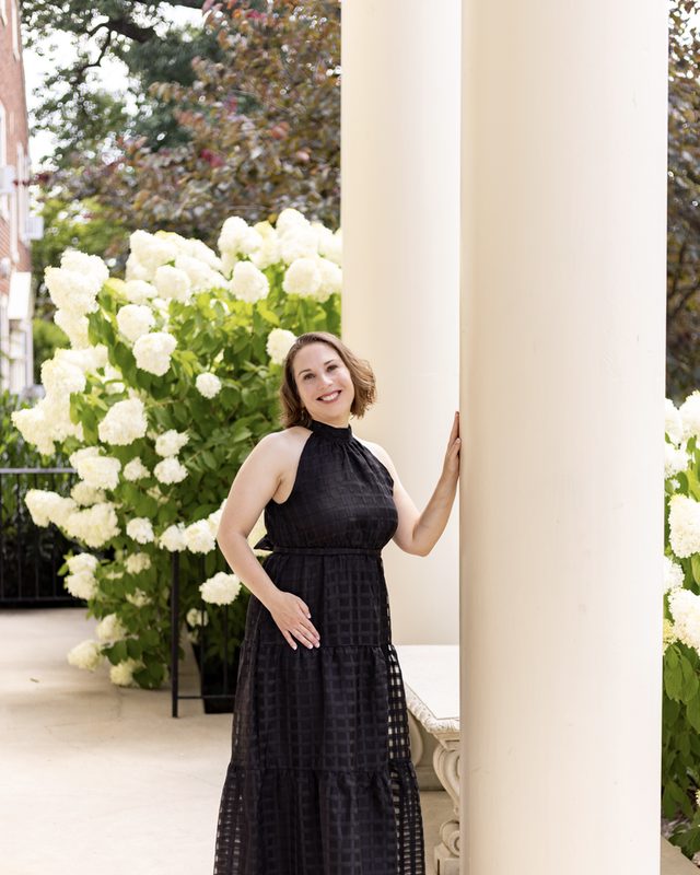 Francesca Merritt standing beside a column, hydrangeas in bloom